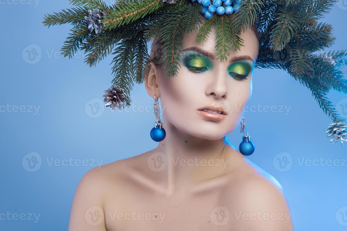 portrait horizontal de jeune jolie femme avec une couronne d'arbre de Noël sur la tête et les yeux fermés photo