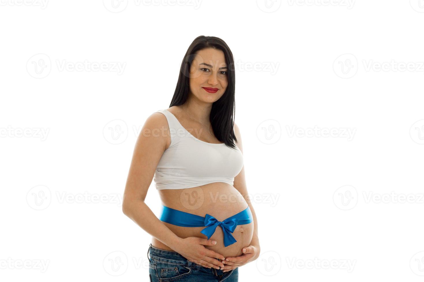 portrait de jeune jolie femme enceinte avec du ruban bleu sur le ventre regarde la caméra isolée sur fond blanc photo