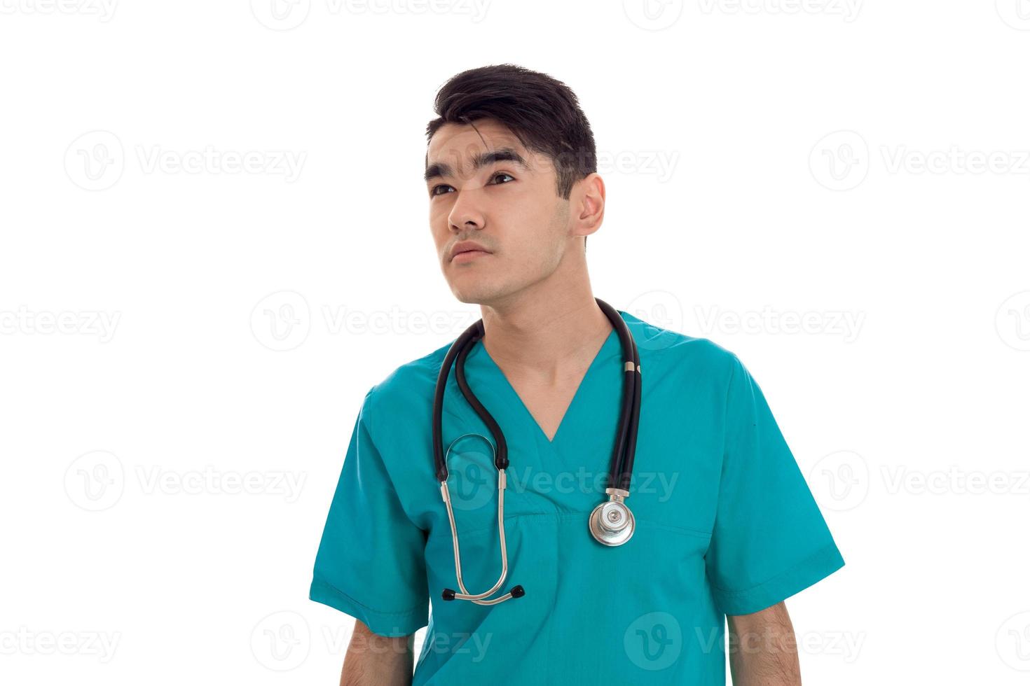 jeune médecin tenant un stéthoscope sur les épaules et regarde vers le gros plan isolé sur fond blanc photo
