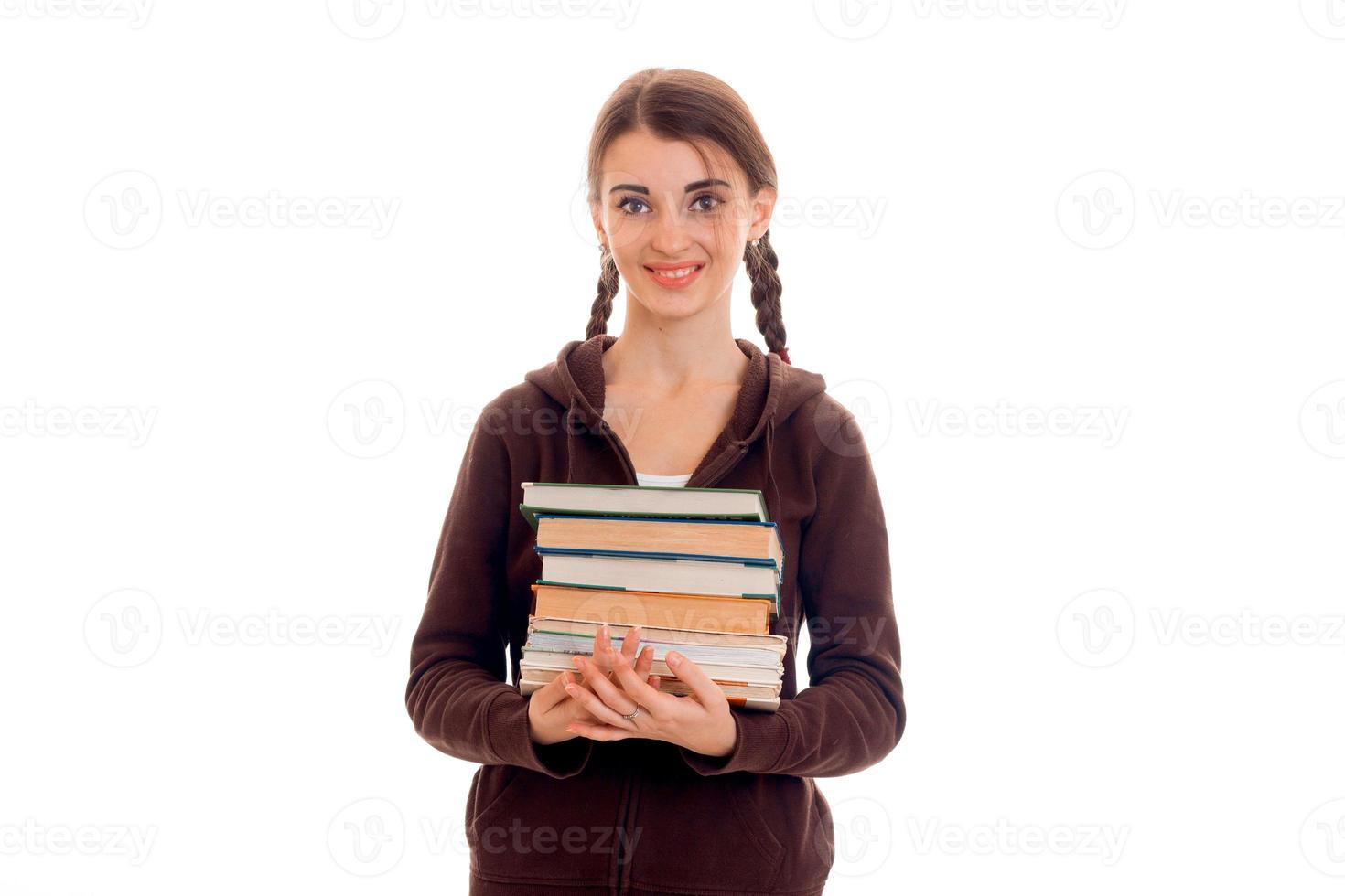 Smiling teen girl with pigtails smortit à droite et détient de nombreux livres photo