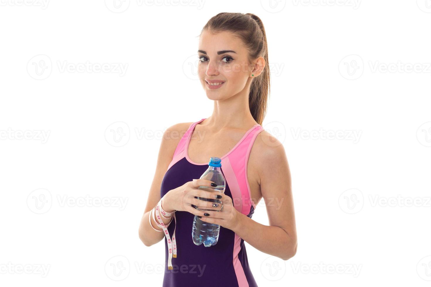 belle fille mince dans un costume de sport souriant a l'air droit et garde l'eau photo