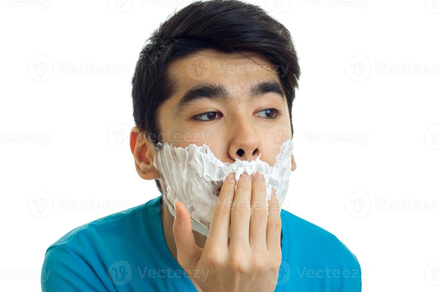 portrait d'un jeune homme ridiculement jeune qui fait de la mousse à raser sur votre visage en gros plan photo