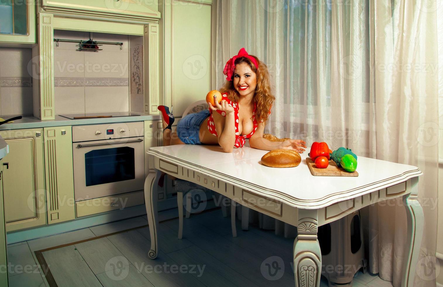 portrait horizontal d'une jeune femme sexuelle posant sur une table dans la cuisine photo