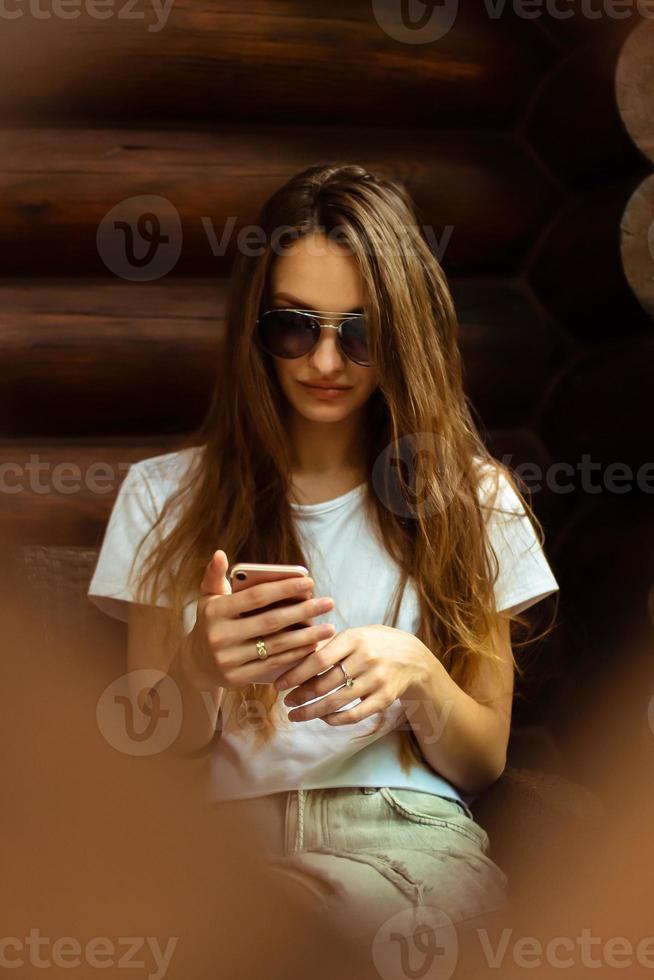 Dame sexy à lunettes de soleil à la maison en bois posant photo