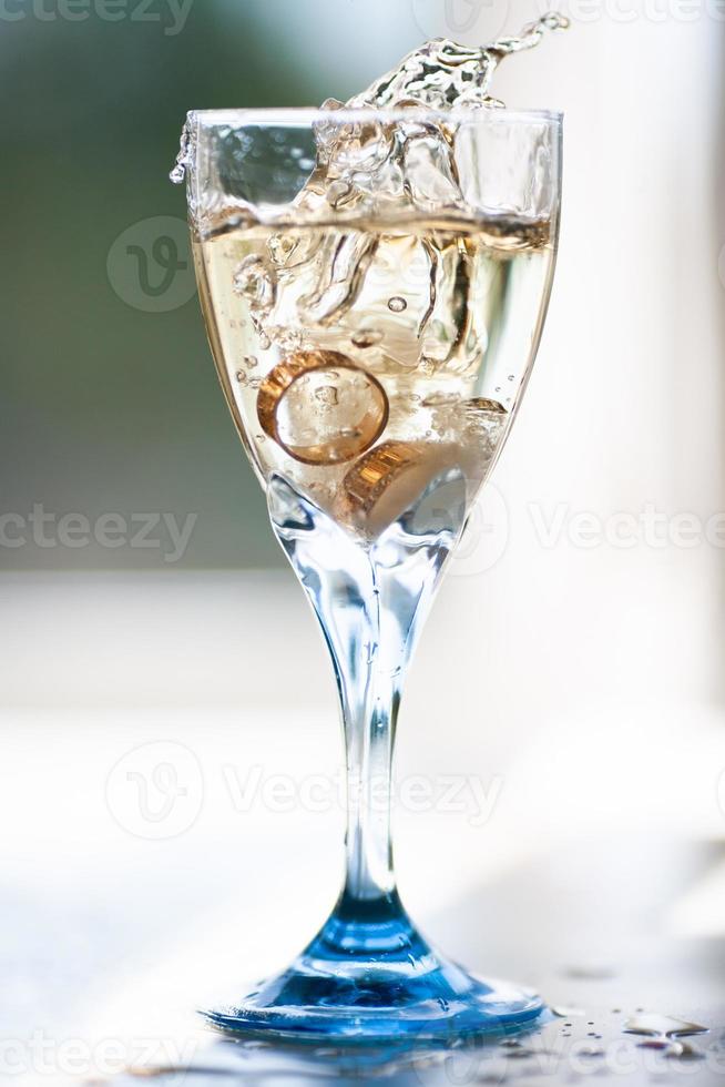 gros plan des anneaux de mariage tombant dans un verre de champagne photo