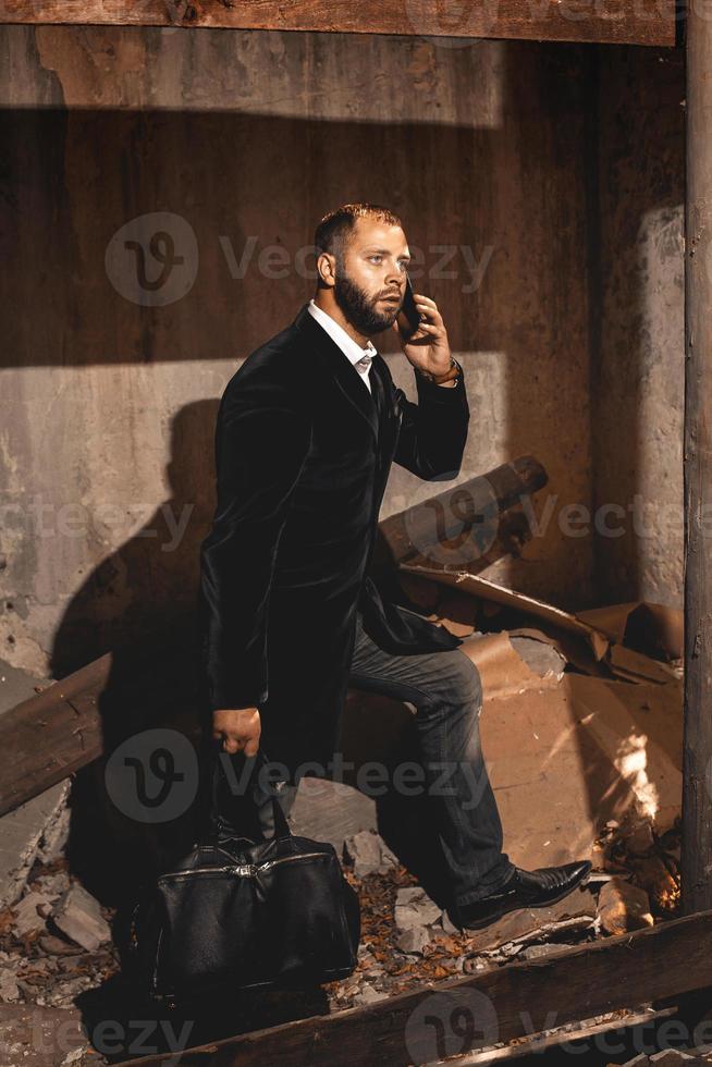 homme en costume noir avec une mallette marchant à l'extérieur et parlant au téléphone photo