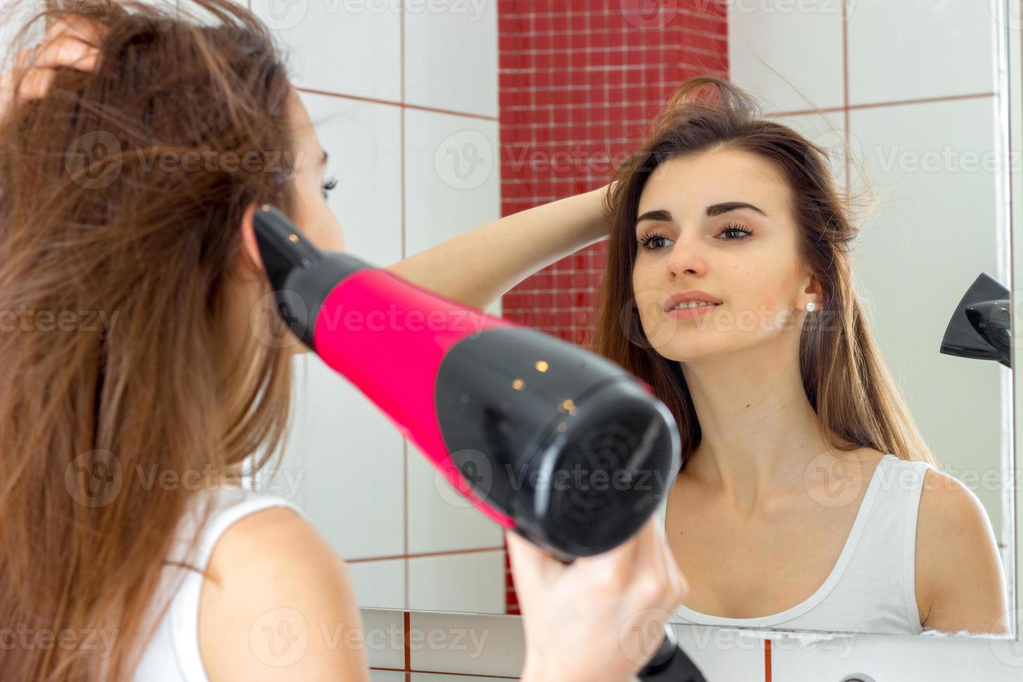 jolie jeune femme séchant un sèche-cheveux photo