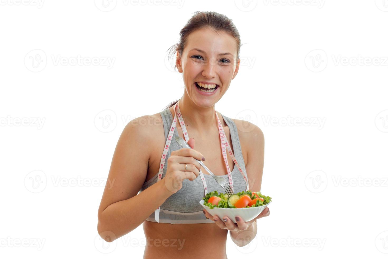 heureuse jeune femme sportive mange de la salade et rit photo