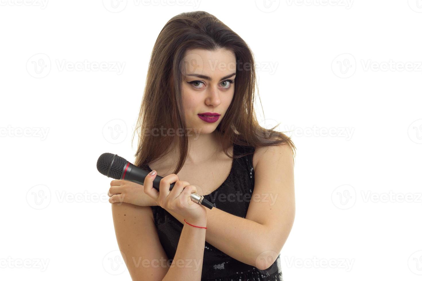 jolie fille brune avec un microphone dans les mains regarde la caméra photo