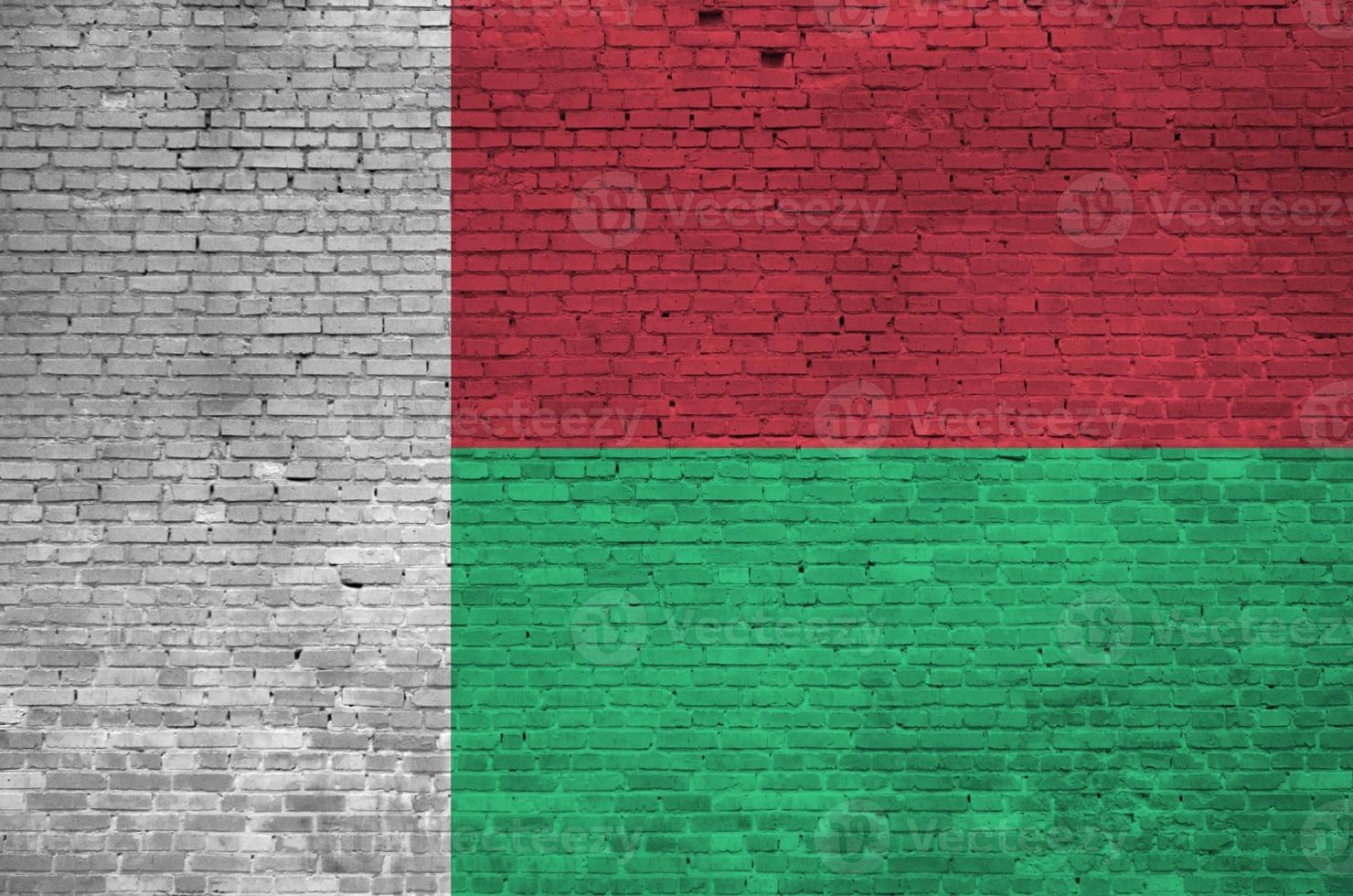 drapeau de madagascar représenté dans des couleurs de peinture sur un vieux mur de briques. bannière texturée sur fond de maçonnerie de gros mur de briques photo