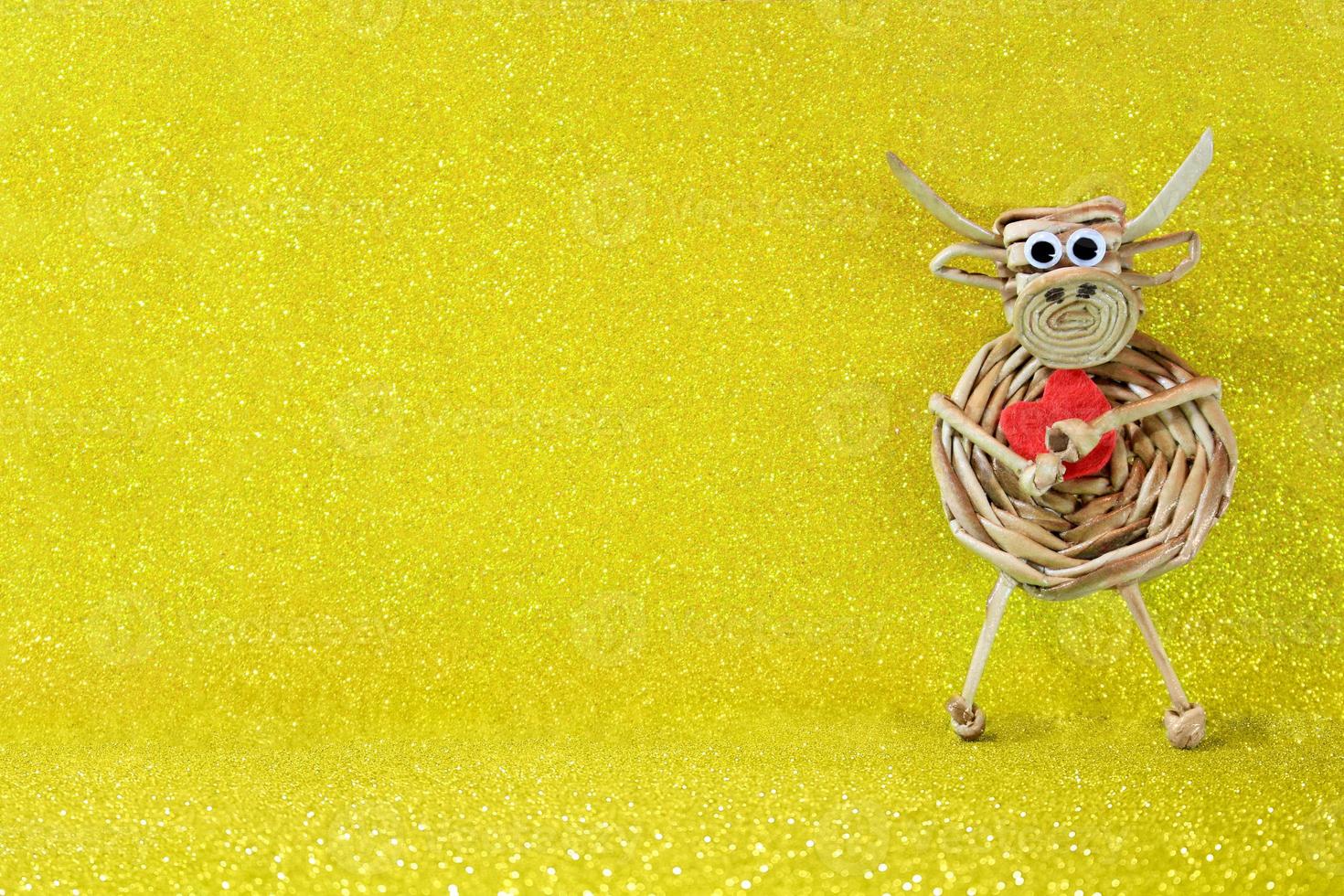le boeuf au coeur rouge se dresse sur fond jaune avec des étincelles. fond de noël et du nouvel an. symbole de l'année. La Saint-Valentin. copie espace photo