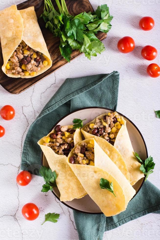 burritos mexicains traditionnels avec de la viande hachée, du maïs et des haricots sur une assiette. vue de dessus et verticale photo