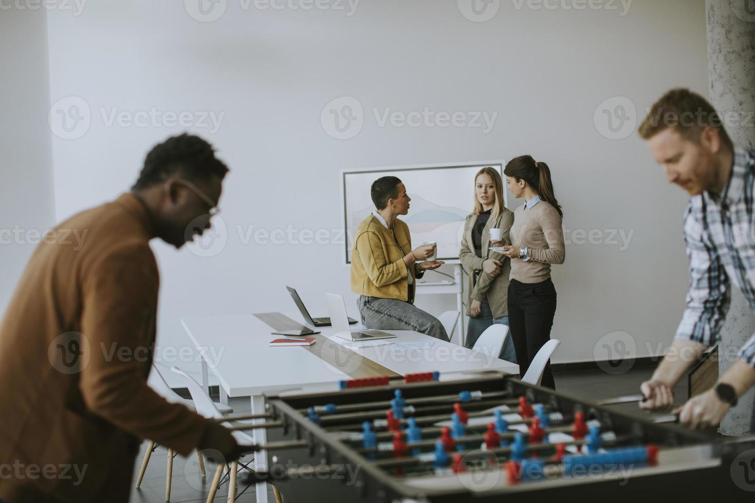 jeunes gens d'affaires multiethniques décontractés jouant au baby-foot et se relaxant au bureau photo