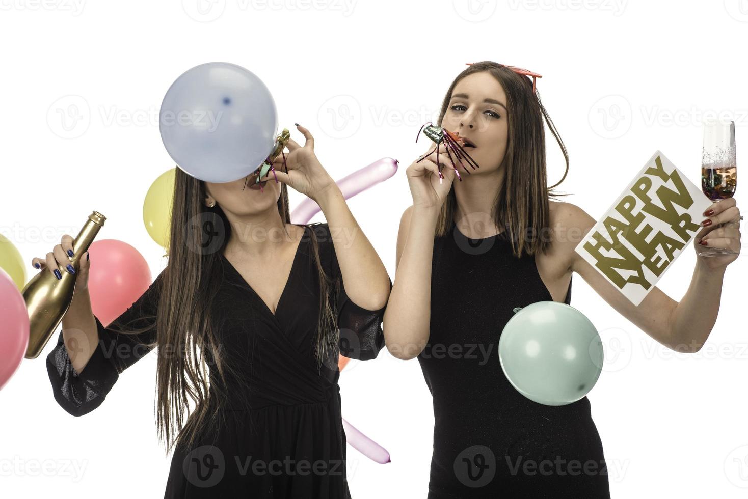 deux amies célébrant le nouvel an avec des confettis et du champagne tenant une pancarte. isolée photo