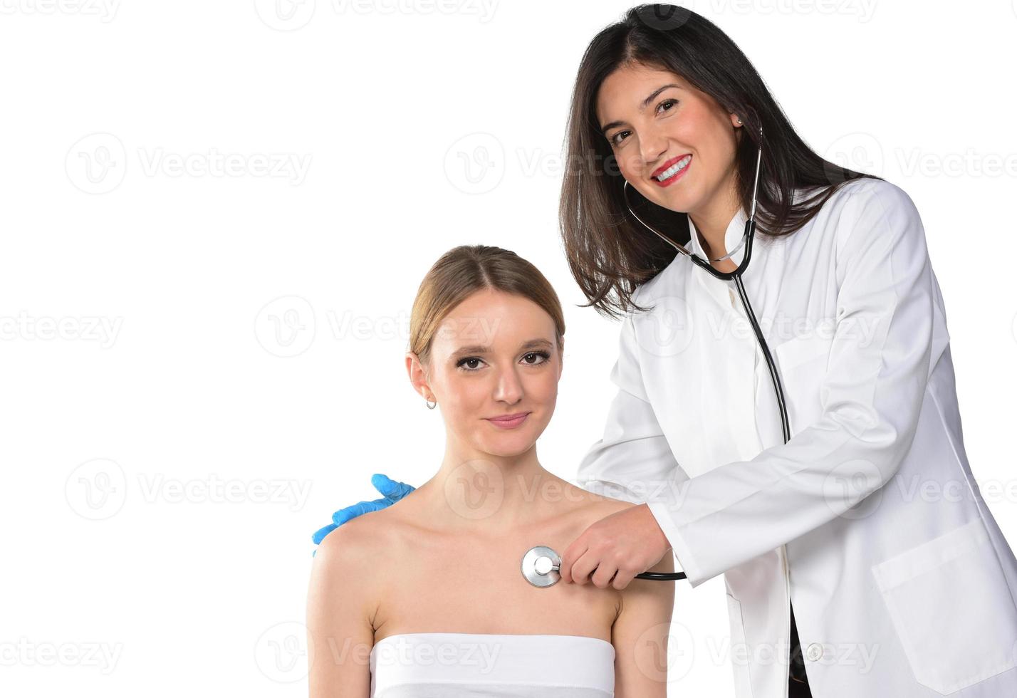 une jeune femme médecin attentionnée dans un masque médical tient un stéthoscope écoute le cœur du patient à l'hôpital. photo