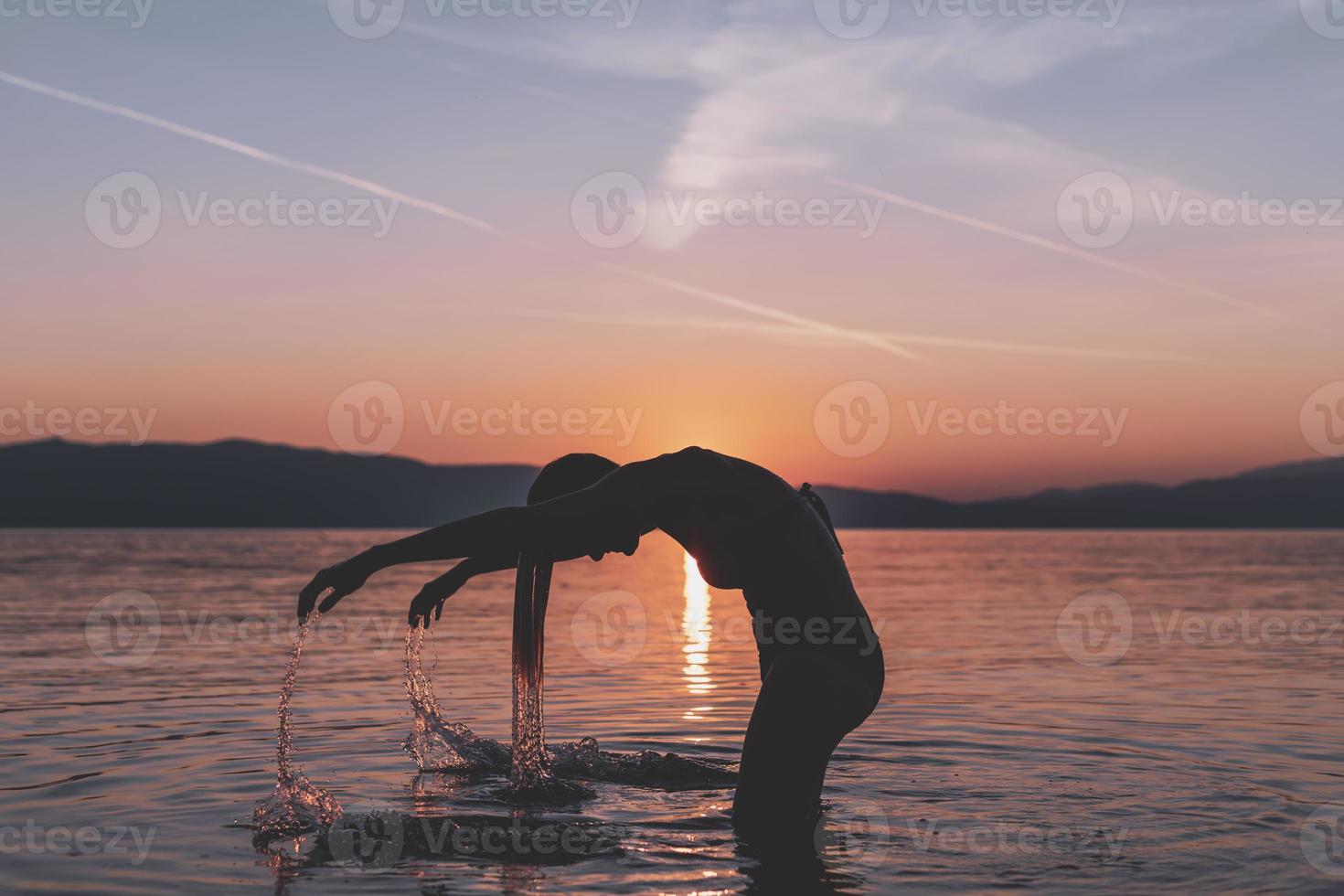 silhouettes de beau modèle féminin au coucher du soleil, lever de soleil sur le fond de la mer, le soleil, les nuages aux couleurs rouge vif, orange photo