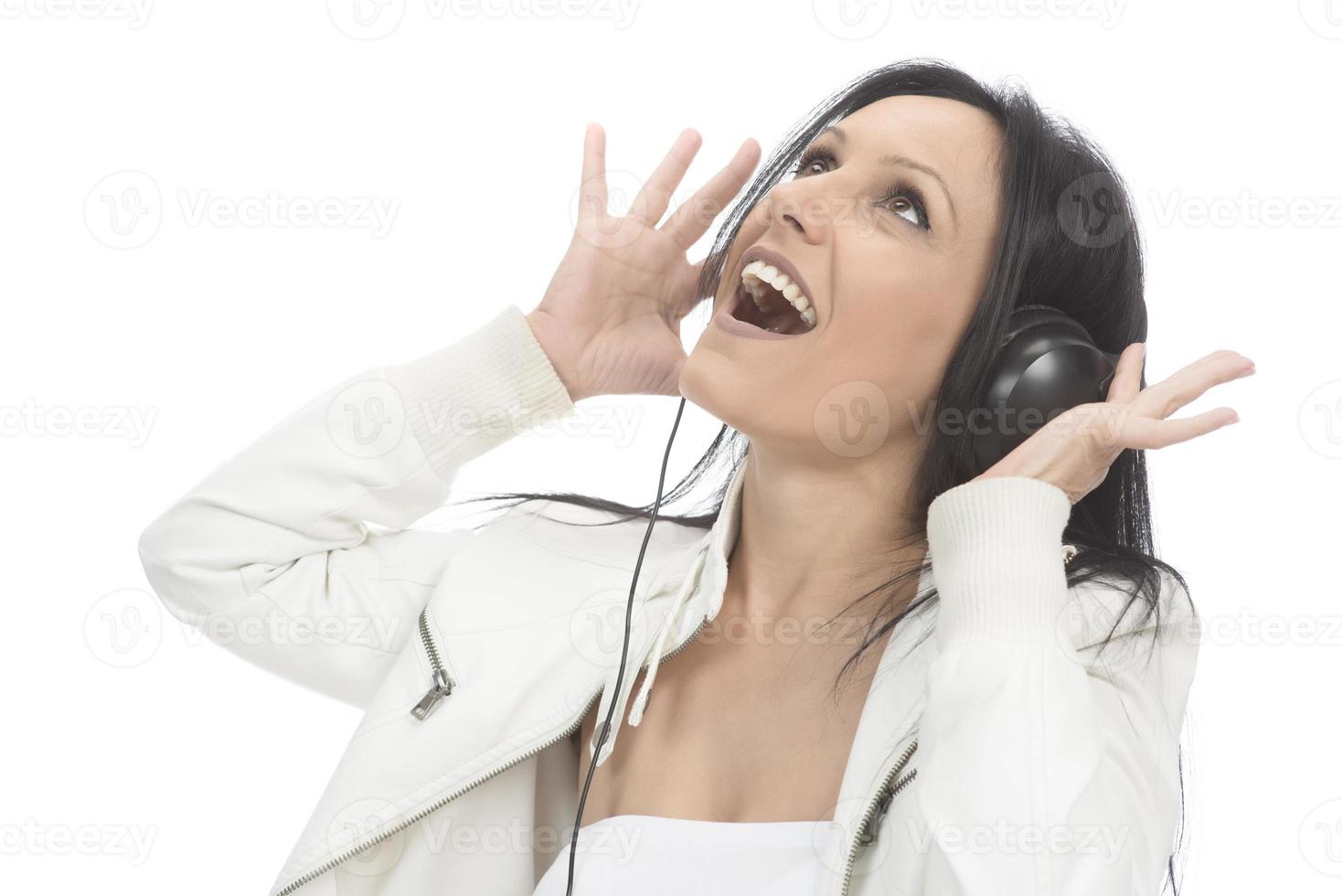 belle fille moderne chantant sa chanson préférée, écoutant de la musique dans des écouteurs sans fil, souriant et dansant photo