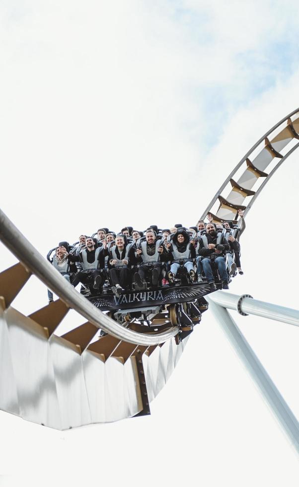 les gens s'amusent dans un parc d'attractions. jeunes amis sur des montagnes russes palpitantes photo