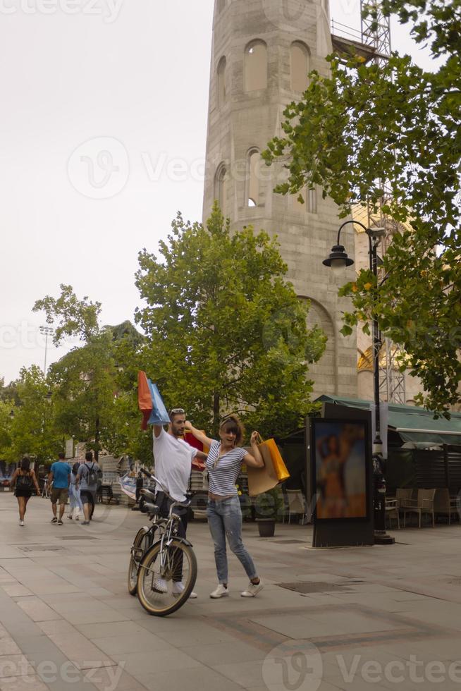 portrait d'un jeune couple caucasien joyeux homme et femme tenant de nombreux sacs en papier après avoir fait du shopping en marchant et en parlant dans la rue. couple de famille heureux avec forfaits en plein air. notion d'achat photo