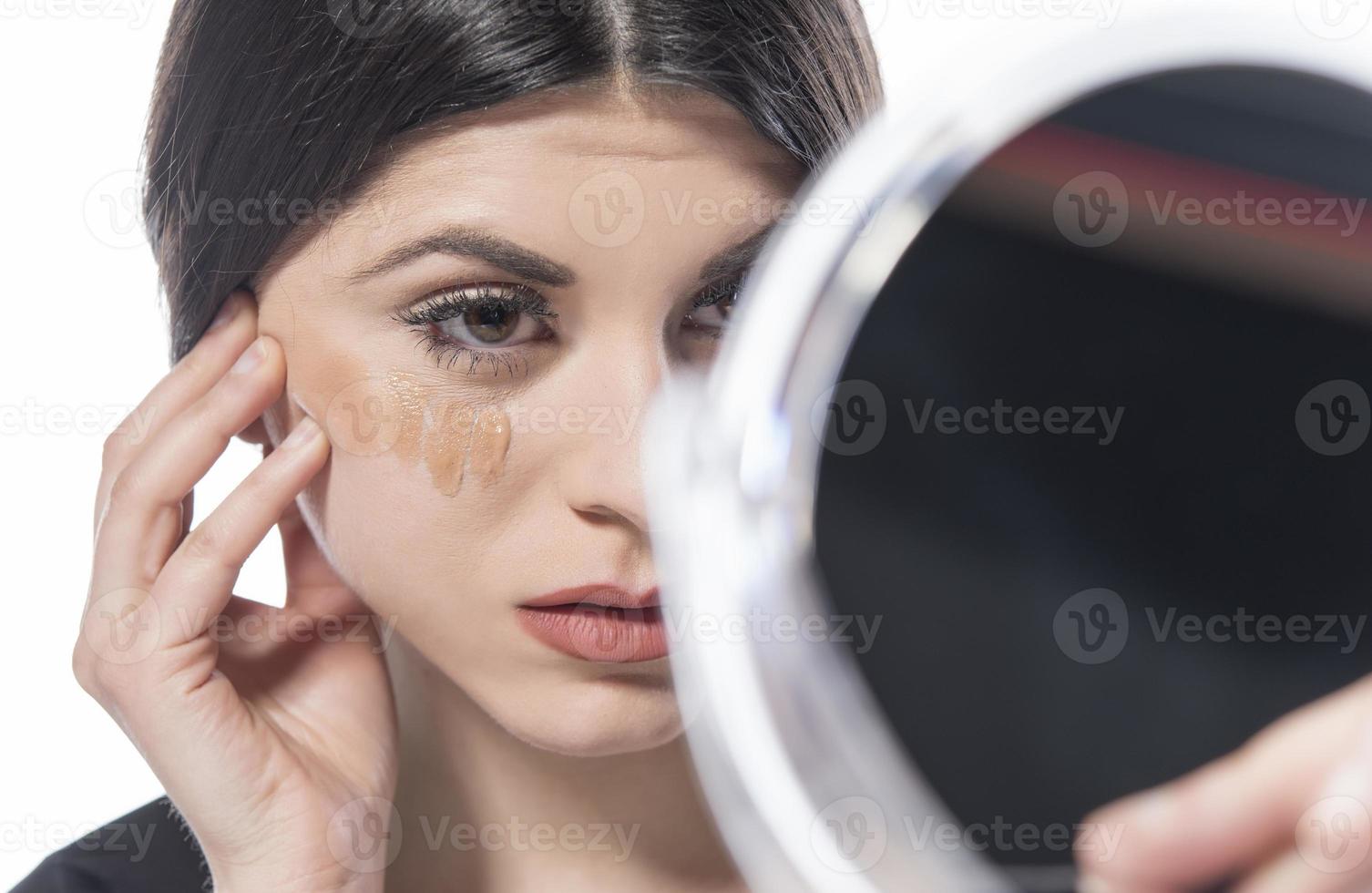 portrait d'une jeune femme appliquant un maquillage liquide sur