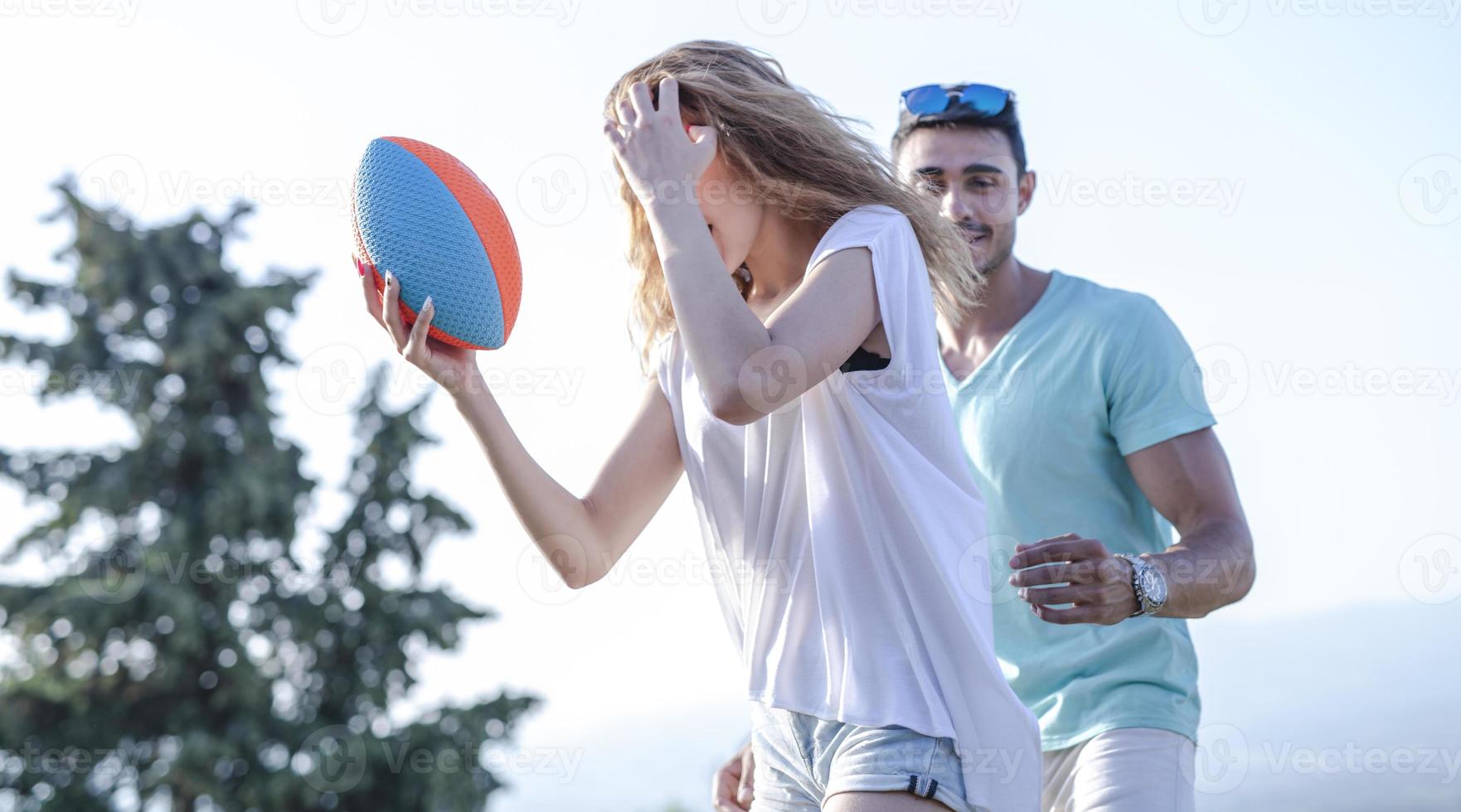 couple jouant au football américain par une chaude journée d'été. séance photo couple jouant au rugby