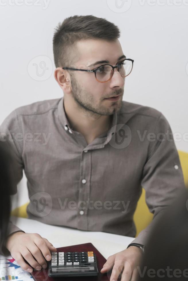 portrait de jeune homme assis à son bureau dans le bureau travaillant sur son ordinateur portable photo