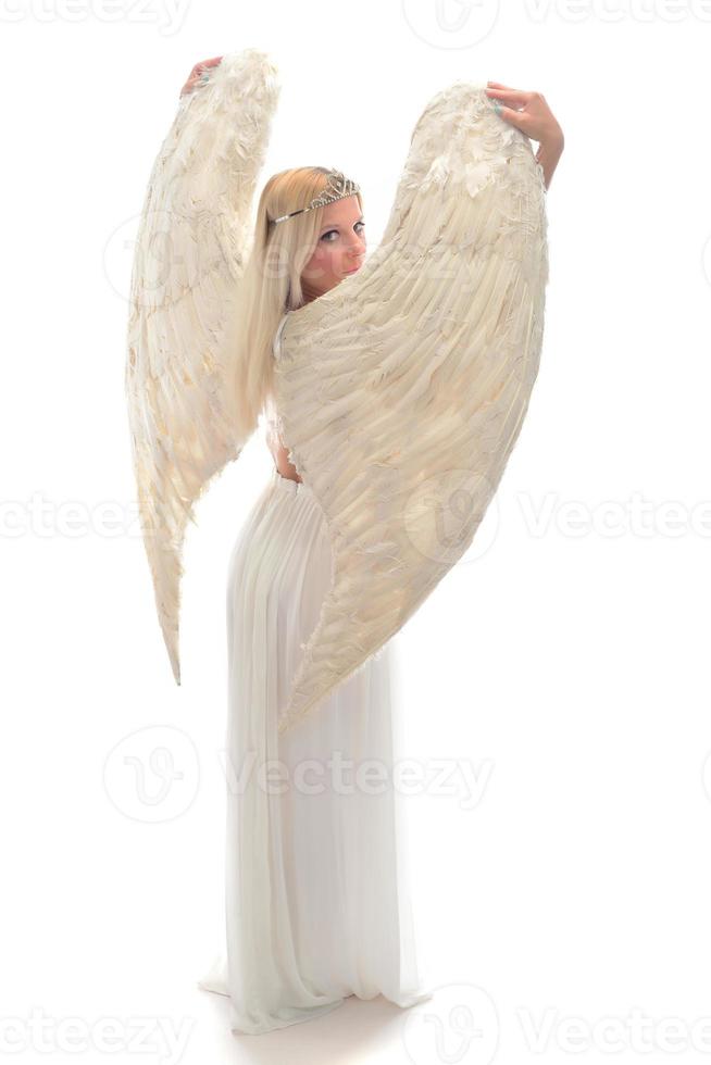 beau jeune mannequin avec de grandes ailes d'ange assis dans le studio. fond blanc photo