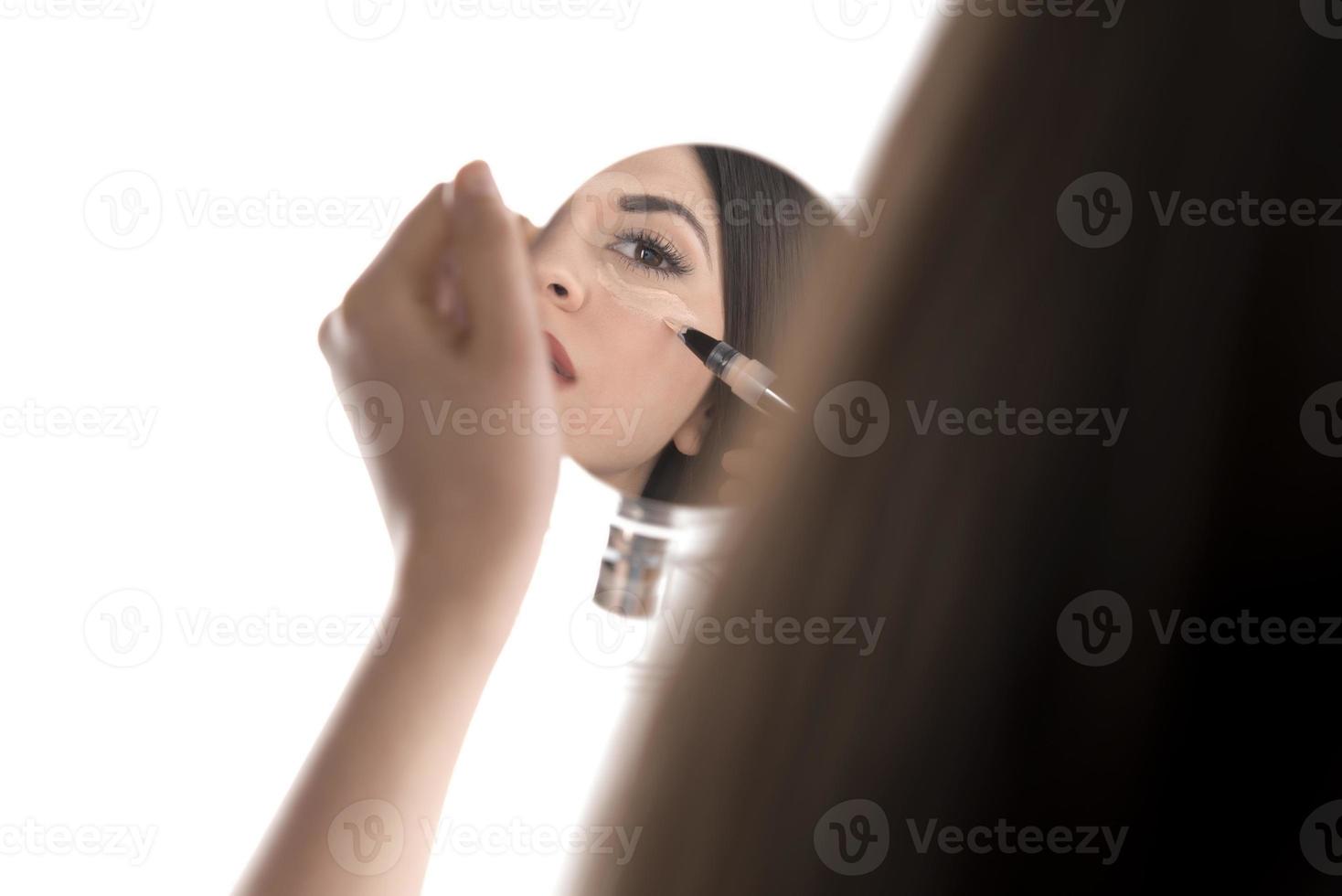 portrait d'une jeune femme appliquant un maquillage liquide sur son visage. isolé sur fond blanc photo