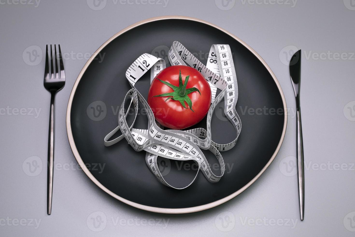tomate et ruban à mesurer sur l'assiette. la notion de régime. photo