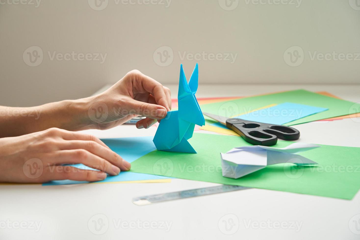 notion de bricolage. femme fait un lapin de pâques origami à partir de papier de couleur. cours d'origami photo