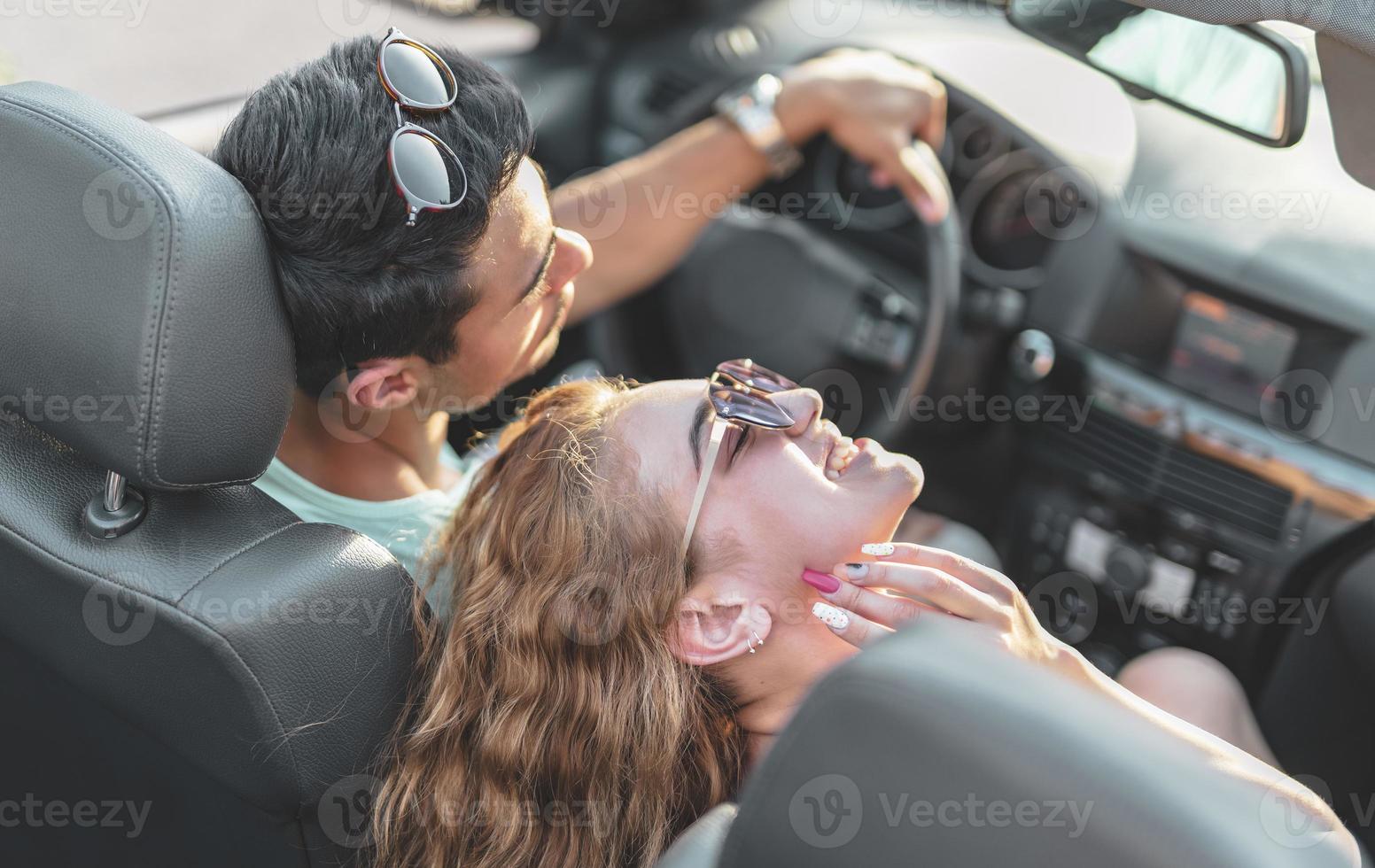 amis s'amusant lors d'un voyage en voiture autour du monde. couple amoureux avec les bras levés sur une voiture décapotable. photo