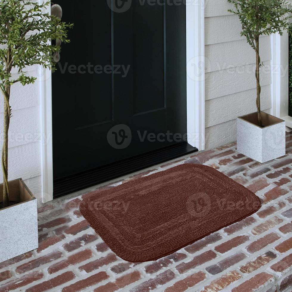 paillasson d'entrée de bienvenue design placé sur un sol en brique solide à l'extérieur de la porte d'entrée avec des plantes photo