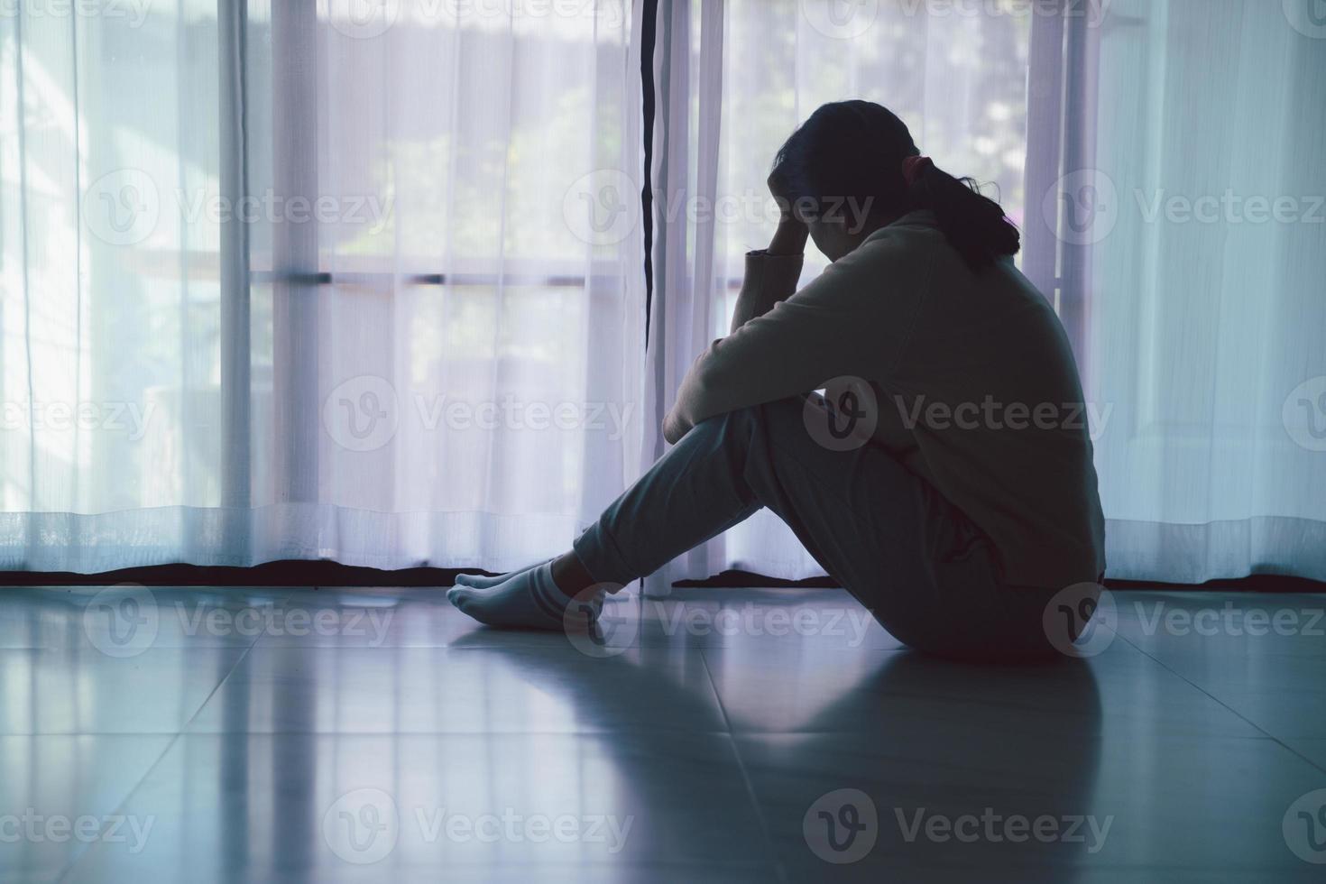 schizophrénie avec concept de dépression solitaire et triste en santé mentale. femme déprimée assise contre le sol à la maison avec une pièce sombre se sentant misérable. les femmes sont déprimées, craintives et malheureuses. photo