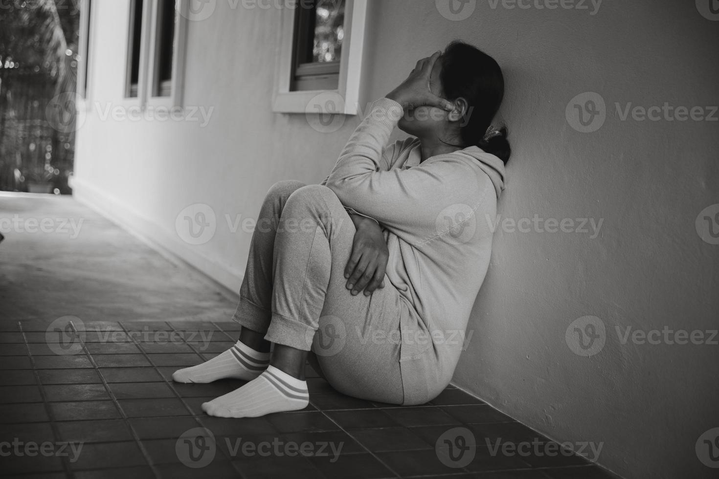 schizophrénie avec concept de dépression solitaire et triste en santé mentale. femme déprimée assise contre le sol à la maison avec une pièce sombre se sentant misérable. les femmes sont déprimées, craintives et malheureuses. photo