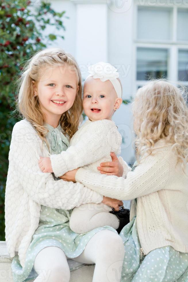 3 petites filles aux cheveux clairs se font un câlin. l'amour des soeurs photo