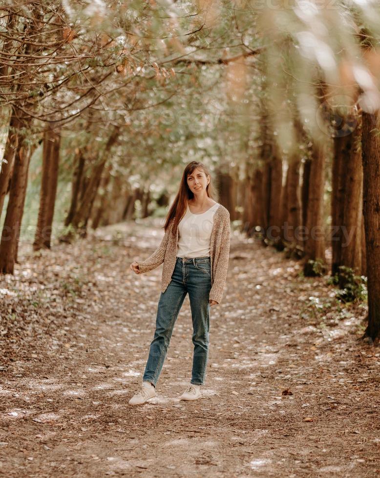 portrait d'une jeune fille aux cheveux bruns, en cardigan, lors d'une promenade en forêt. photo