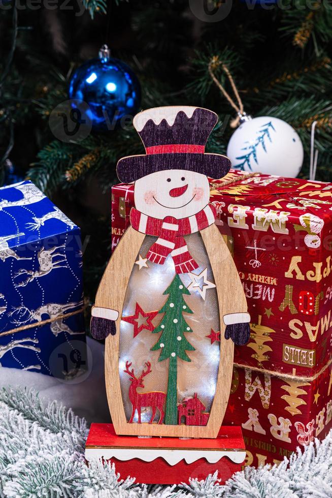 décorations de noël sur fond flou. petit bonhomme de neige en bois. bonhomme de neige en bois rustique flocon de neige gros plan d'un bonhomme de neige heureux souriant avec les bras vers le haut. carte de voeux joyeuses fêtes. photo