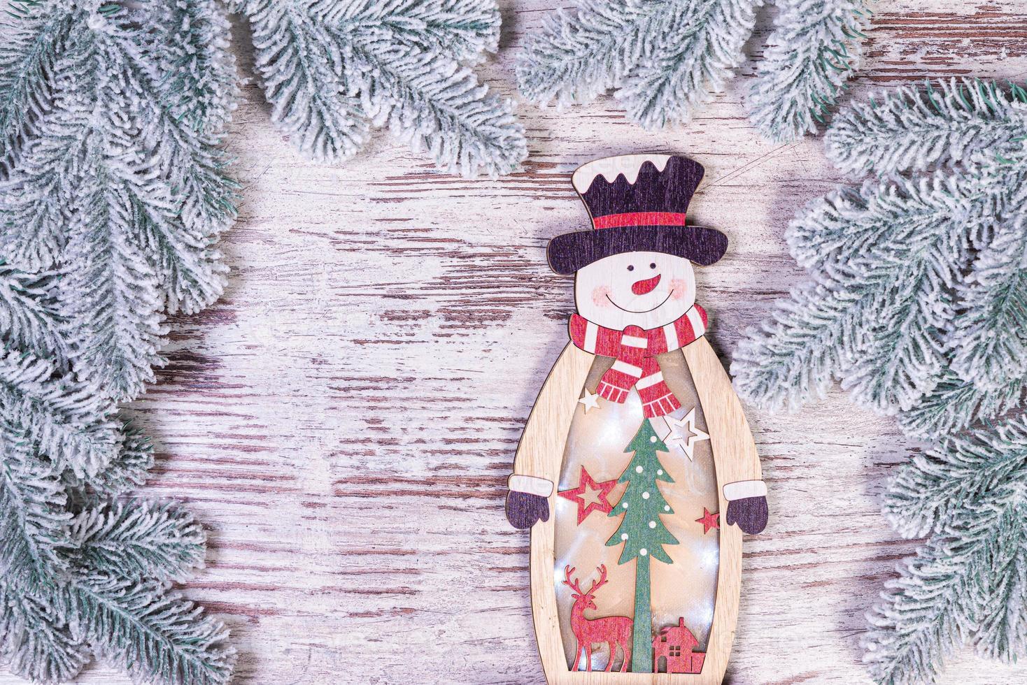 décorations de noël sur fond flou. petit bonhomme de neige en bois. bonhomme de neige en bois rustique flocon de neige gros plan d'un bonhomme de neige heureux souriant avec les bras vers le haut. carte de voeux joyeuses fêtes. photo