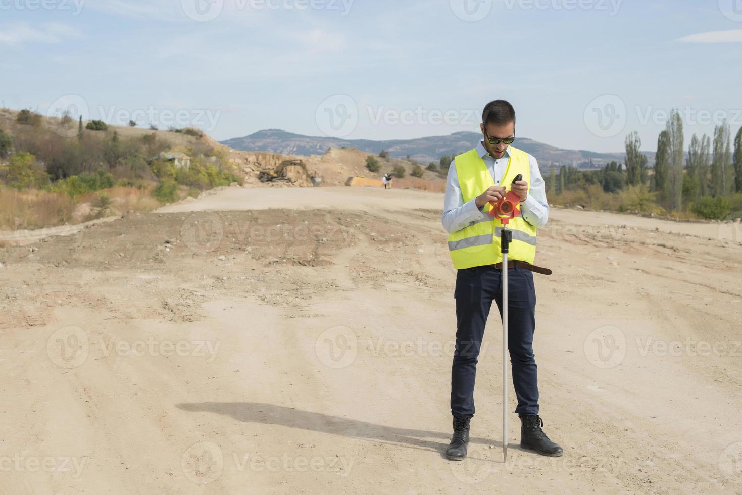 l'ingénieur géomètre mesure le niveau sur le chantier de construction. les géomètres assurent des mesures précises avant d'entreprendre de grands projets de construction. photo