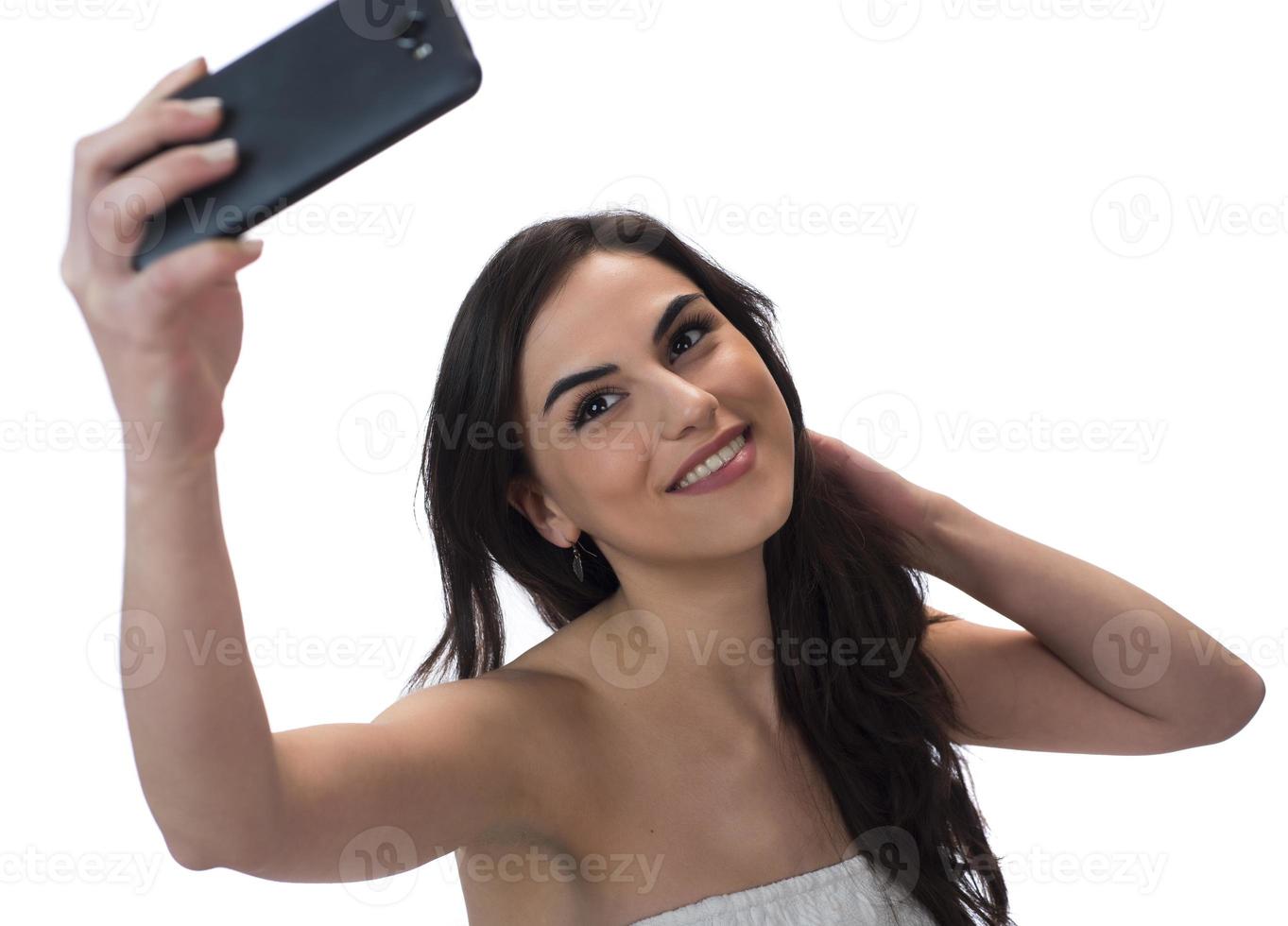 image d'une belle femme brune riant tout en prenant une photo de selfie sur un téléphone portable isolé sur fond blanc