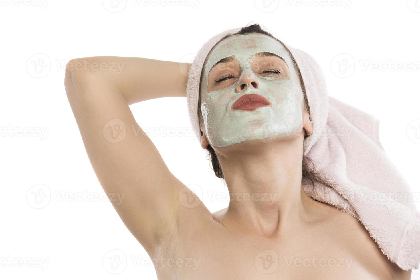 belle jeune femme avec une serviette enroulée autour de sa tête en appliquant un masque facial à l'argile dans la salle de bain photo