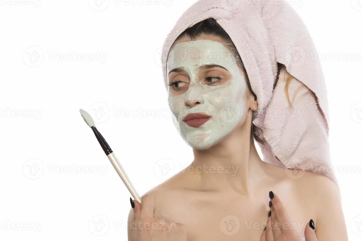 belle femme ayant un masque facial à l'argile appliqué par une esthéticienne. photo