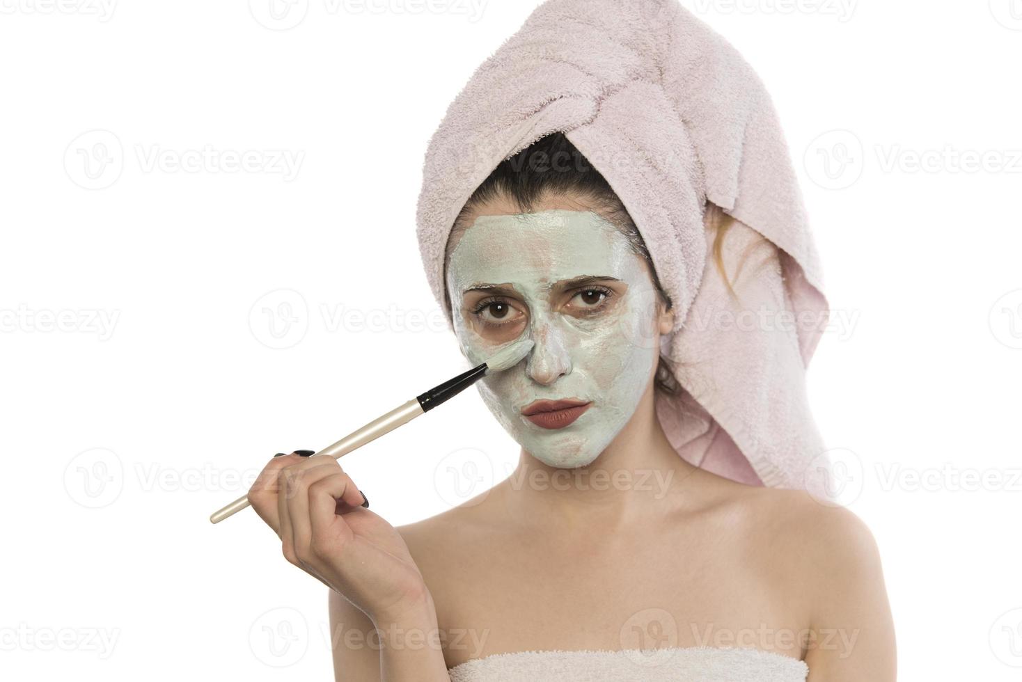 belle femme ayant un masque facial à l'argile appliqué par une esthéticienne. photo