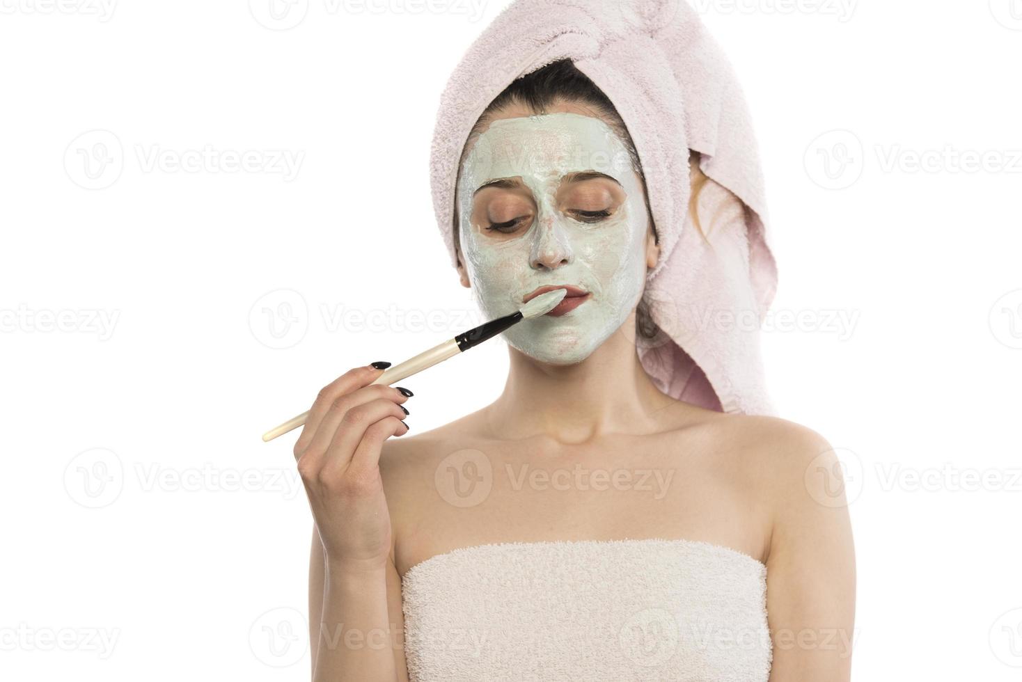 belle femme ayant un masque facial à l'argile appliqué par une esthéticienne. photo