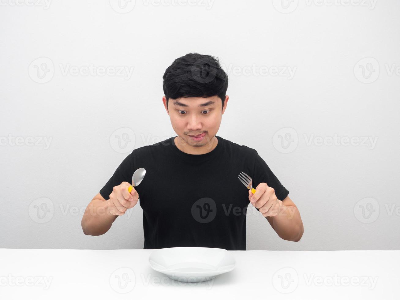 homme affamé tenant un geste de coutellerie prêt à manger le dîner sur la table photo