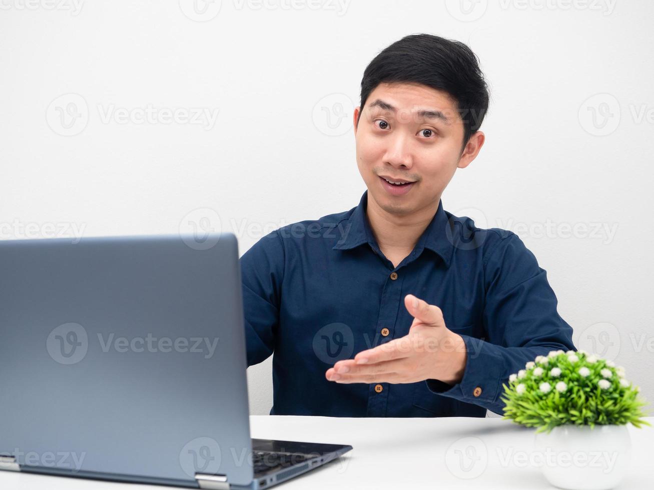 homme asiatique travaillant en ligne avec un ordinateur portable regardant la caméra assis à la table photo