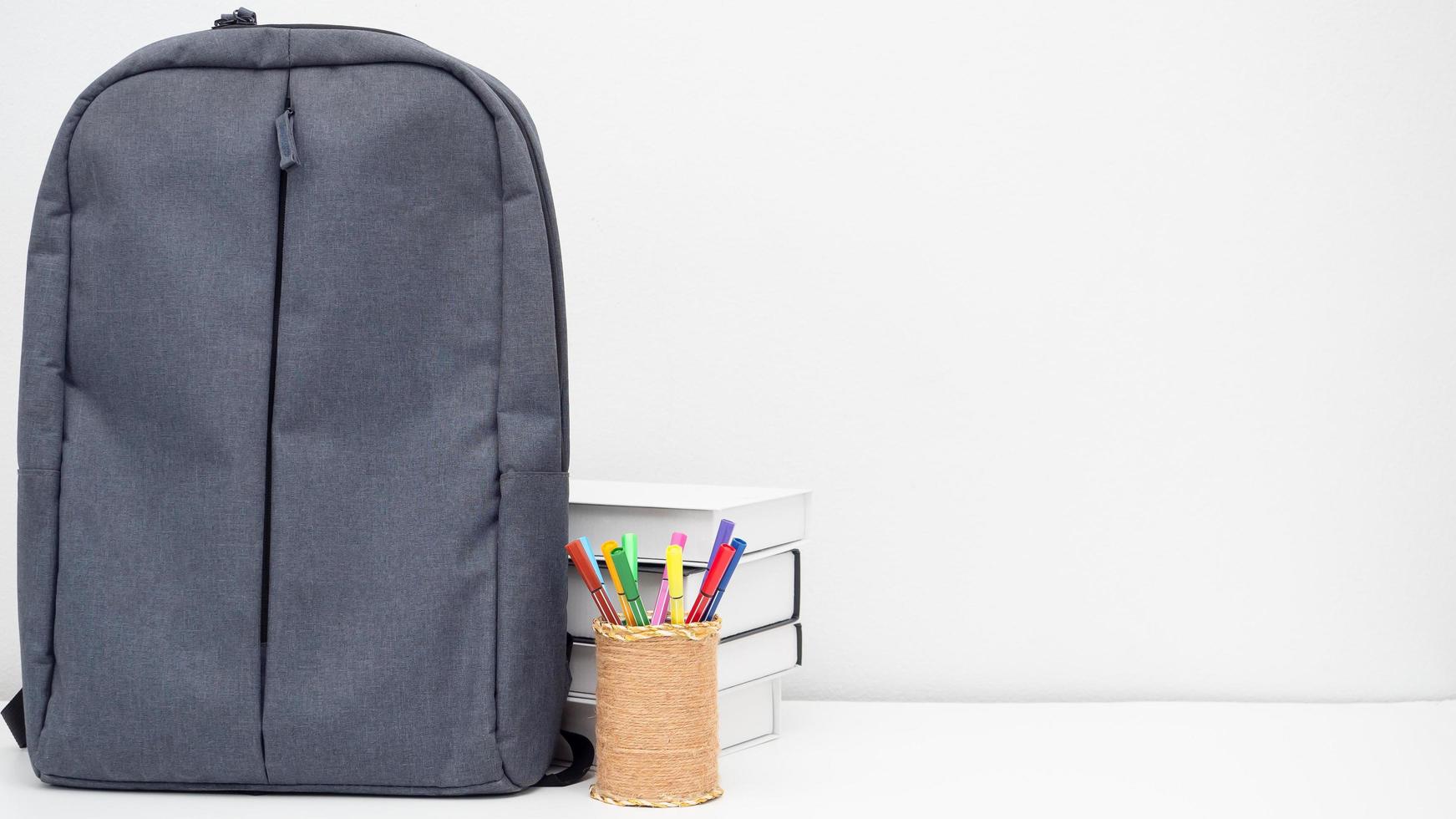 sac d'école avec boîte à crayons et livres sur le bureau espace de copie de fond blanc photo