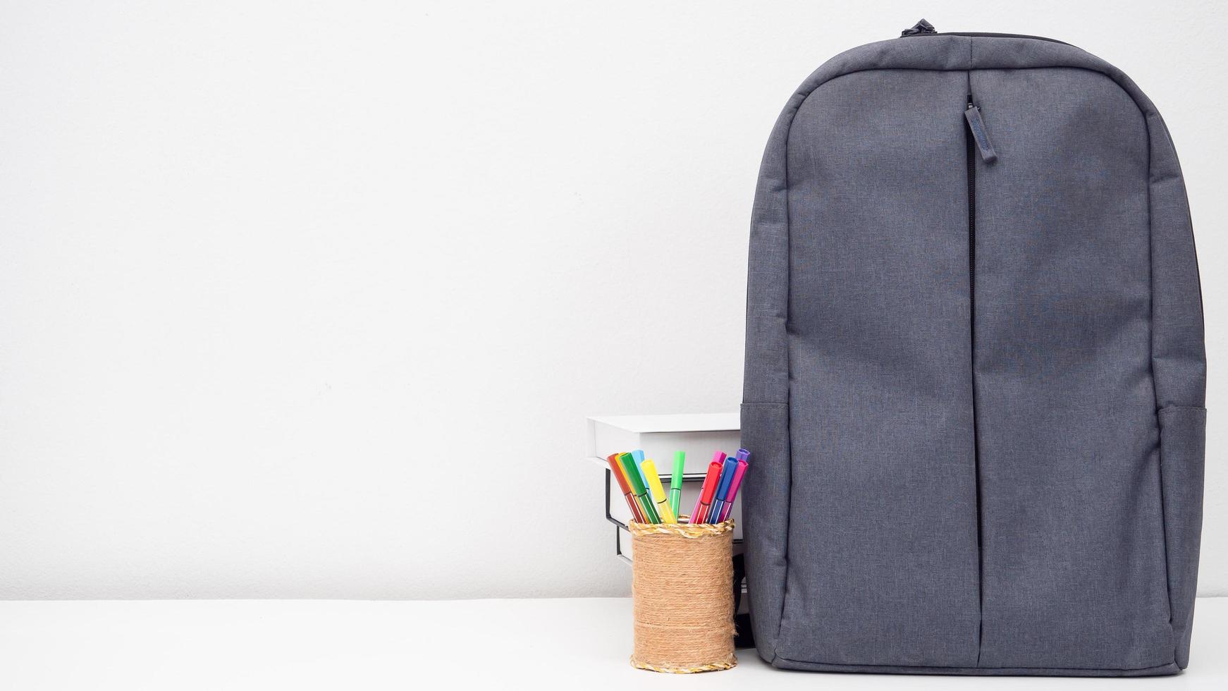 sac d'école avec boîte à crayons et livres sur le bureau espace de copie de fond blanc photo