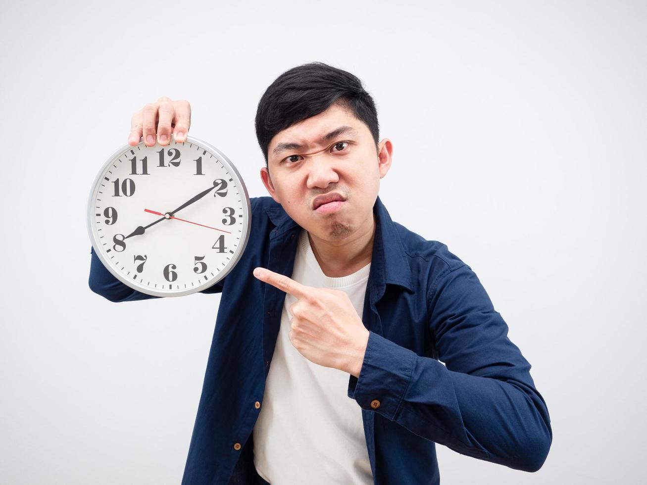 Homme asiatique en colère point de visage à l'horloge dans sa main travail fin concept fond blanc photo