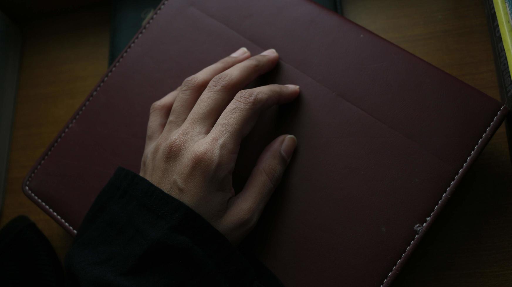 Libre de la main d'une femme sur un livre dans un cadre sombre photo